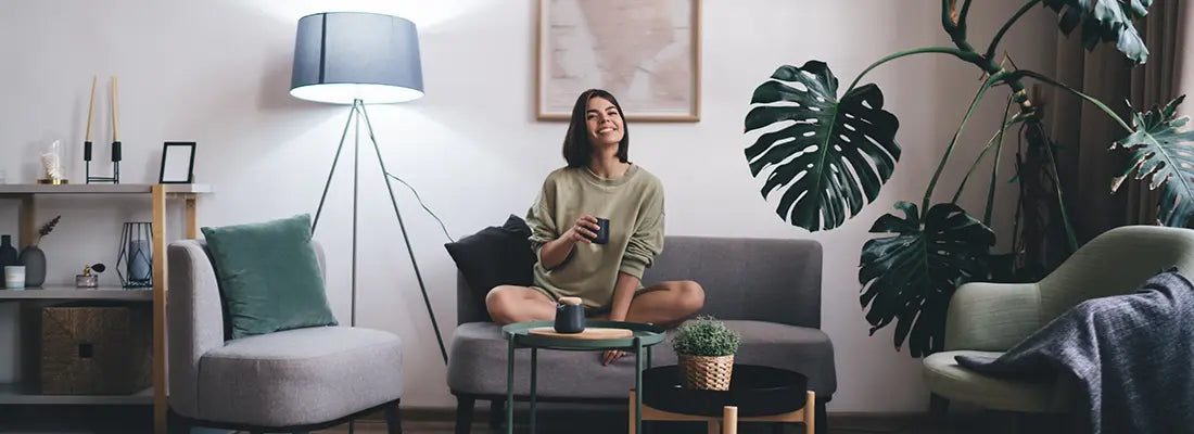 young woman smiling on a couch, holding mug