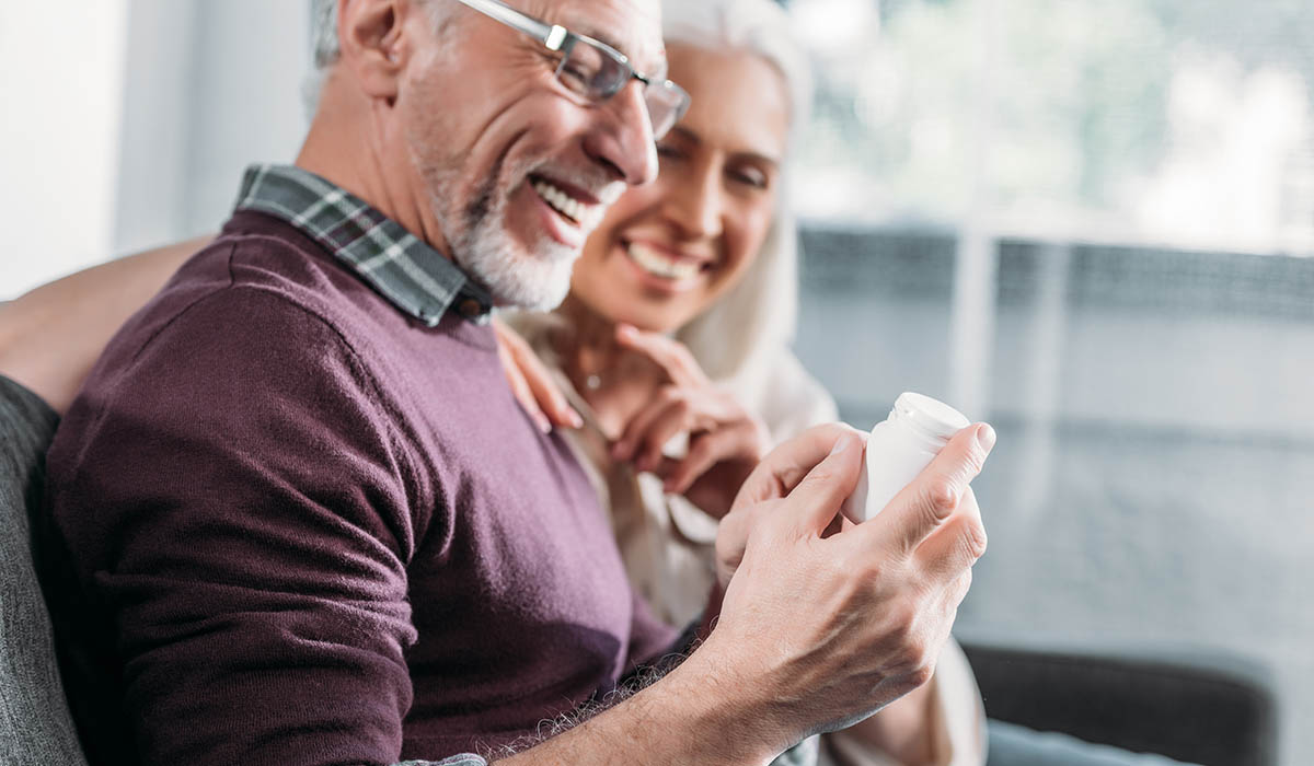 happy older couple holds bottle of supplements for seniors