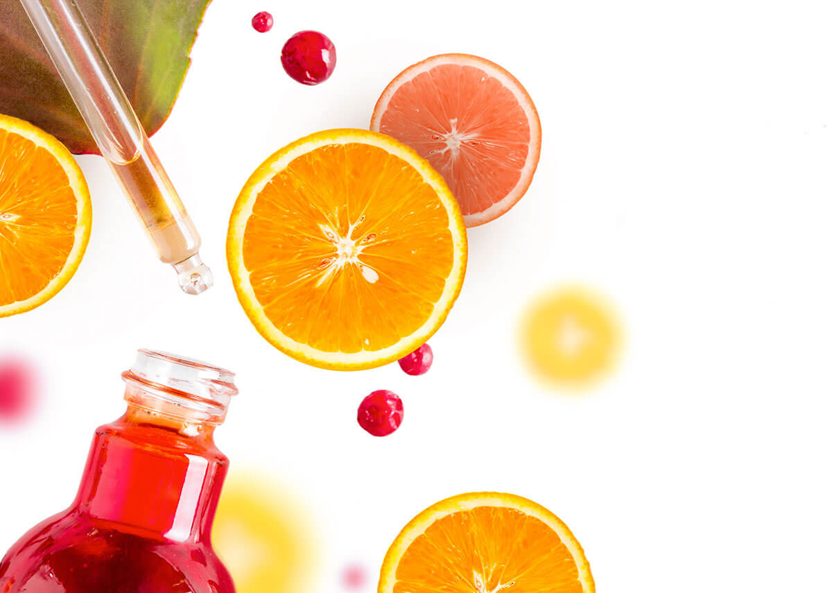 sliced oranges with dropper and bottle containing vitamin c for skin serum