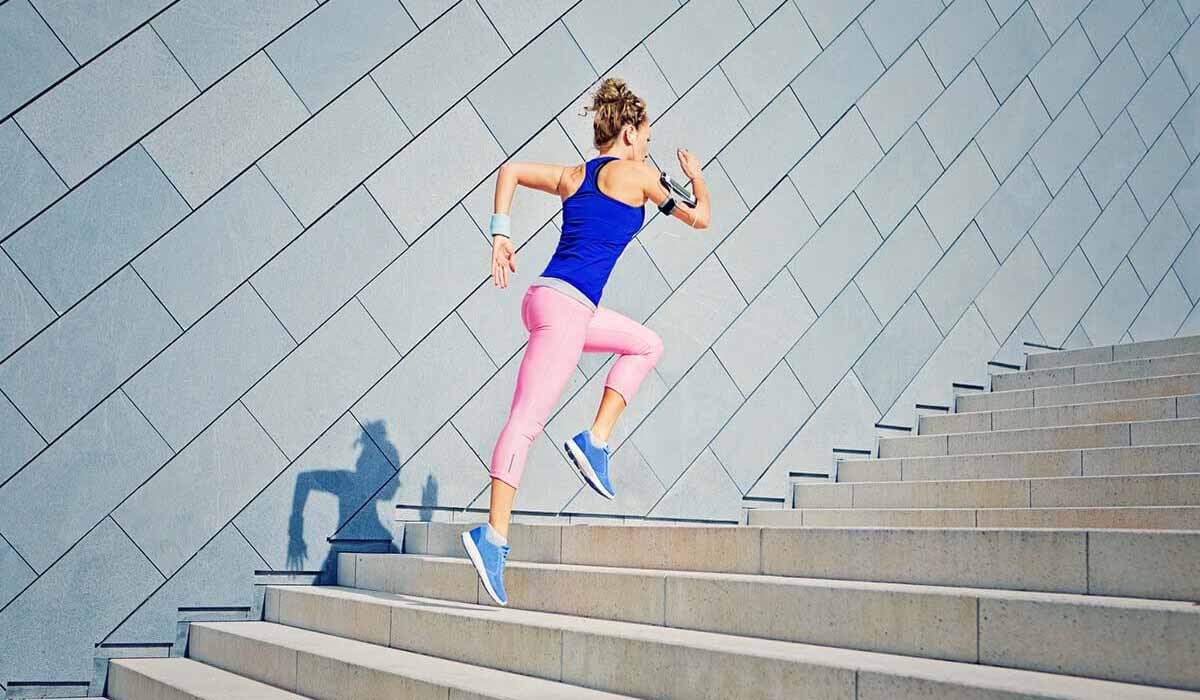 woman in fitness gear running up a flight of steps