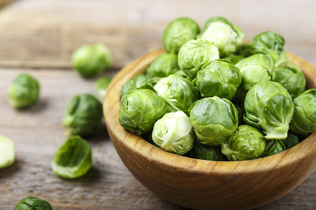 fresh brussels sprouts raw in a plate on wooden board