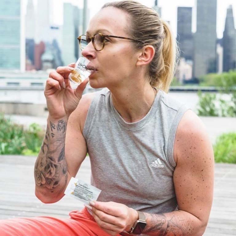 Ambassador Sabrina Wieser drinking shot of lypo-spheric magnesium outdoors with NYC in background