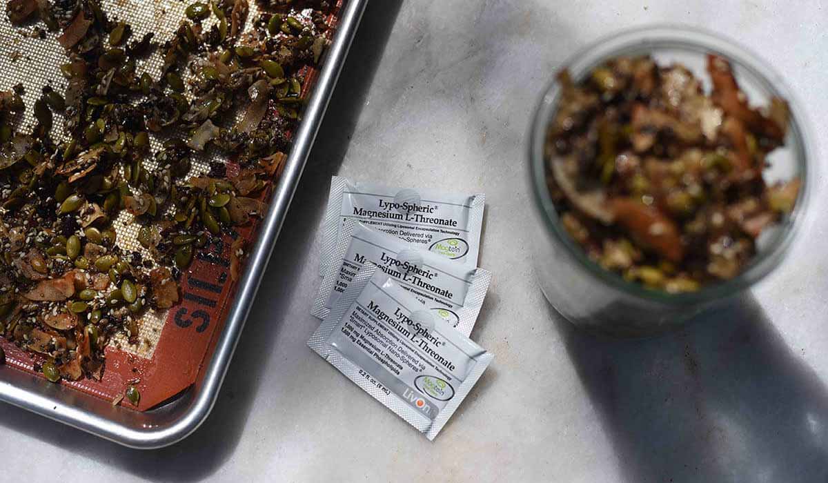 seeded granola on baking sheet with packets of lypo-spheric magnesium