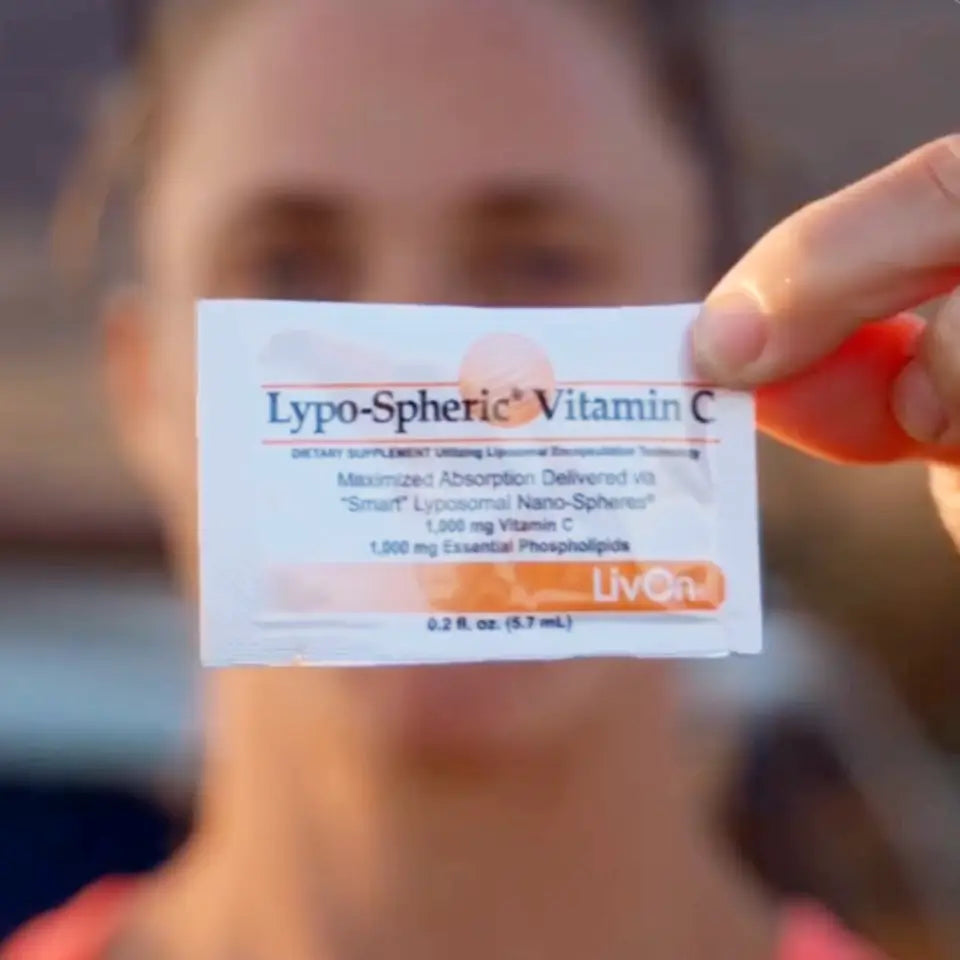packet of lypo-spheric vitamin c held by woman blurred in background