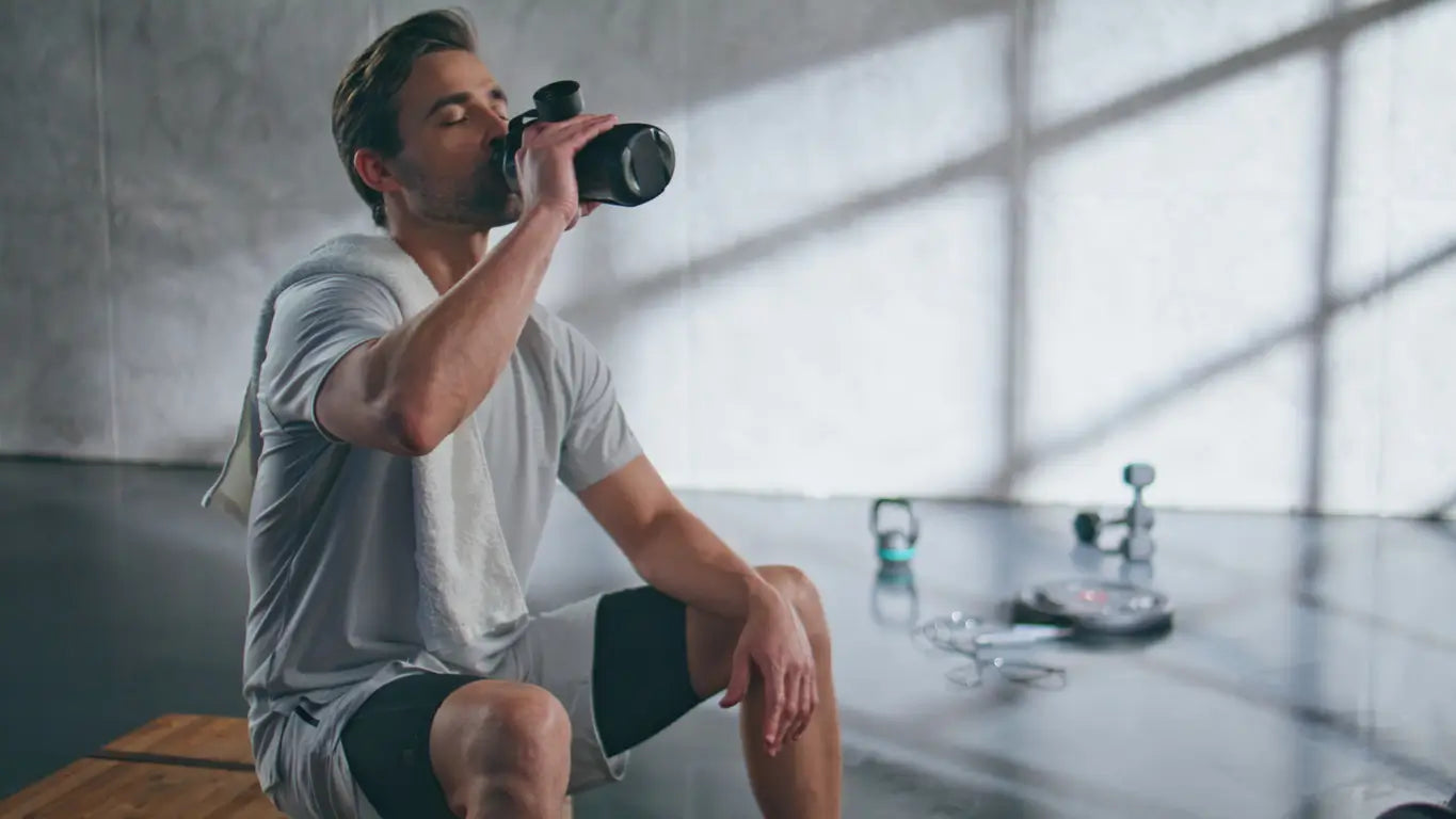 Man drinking from a water bottle in a modern indoor setting