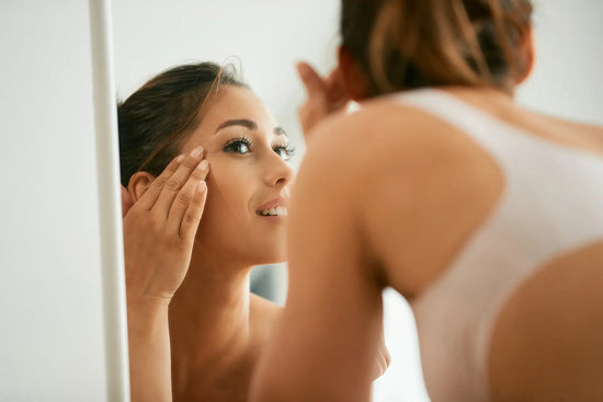young woman looking at her face in mirror