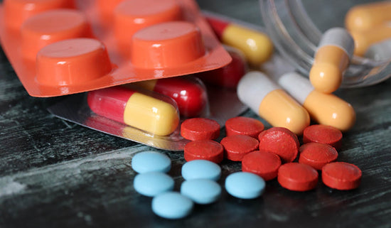 Pills and capsules on dark wooden table, a lot of multicolored medication close-up