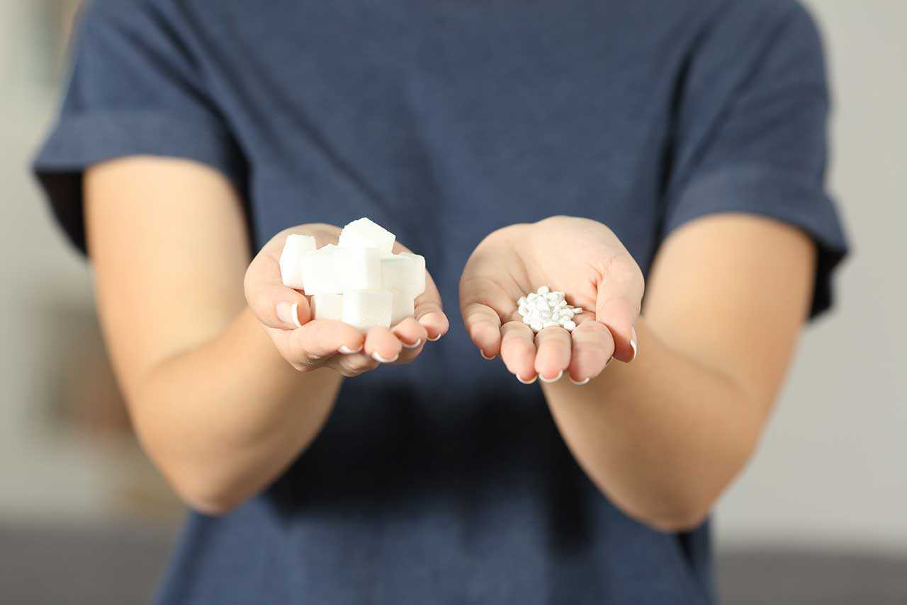 woman holding pills in one hand and sugar cubes in the other