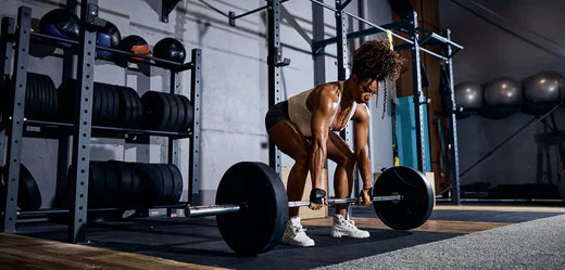 young woman deadlifting a barbell at a gym to build muscle