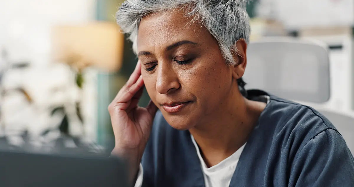 woman with gray hair and hand on temple experiencing menopause brain fog
