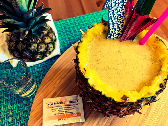 overhead photo of the immuni-tiki immune support smoothie in a pineapple with a packet of lypo-spheric vitamin c