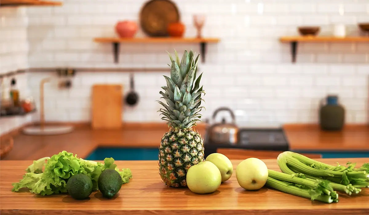 pineapple and vegetables on a counter in a kitchen