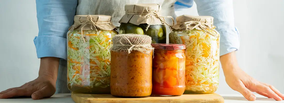 jars of fermented foods on a counter with person standing behind it