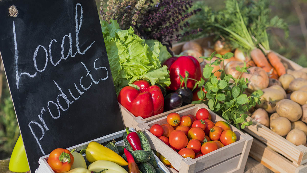 Counter with fresh vegetables and a sign of local produce that help maximize nutrients