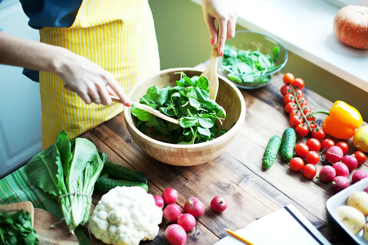 person in apron making a salad