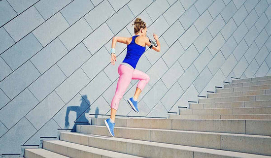 woman in fitness gear running up a flight of steps