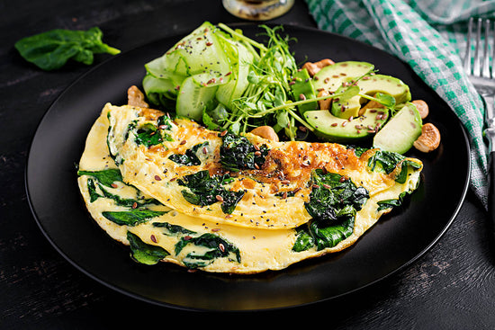 Omelette with spinach along with avocado and cucumber illustrates nutrient pairings for vitamin absorption