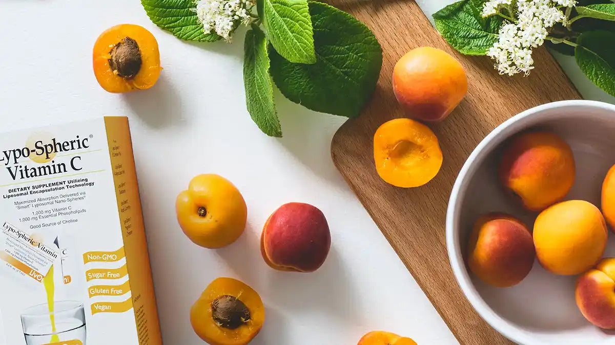 carton of lypo spheric® vitamin c on white surface with wooden cutting board and peaches