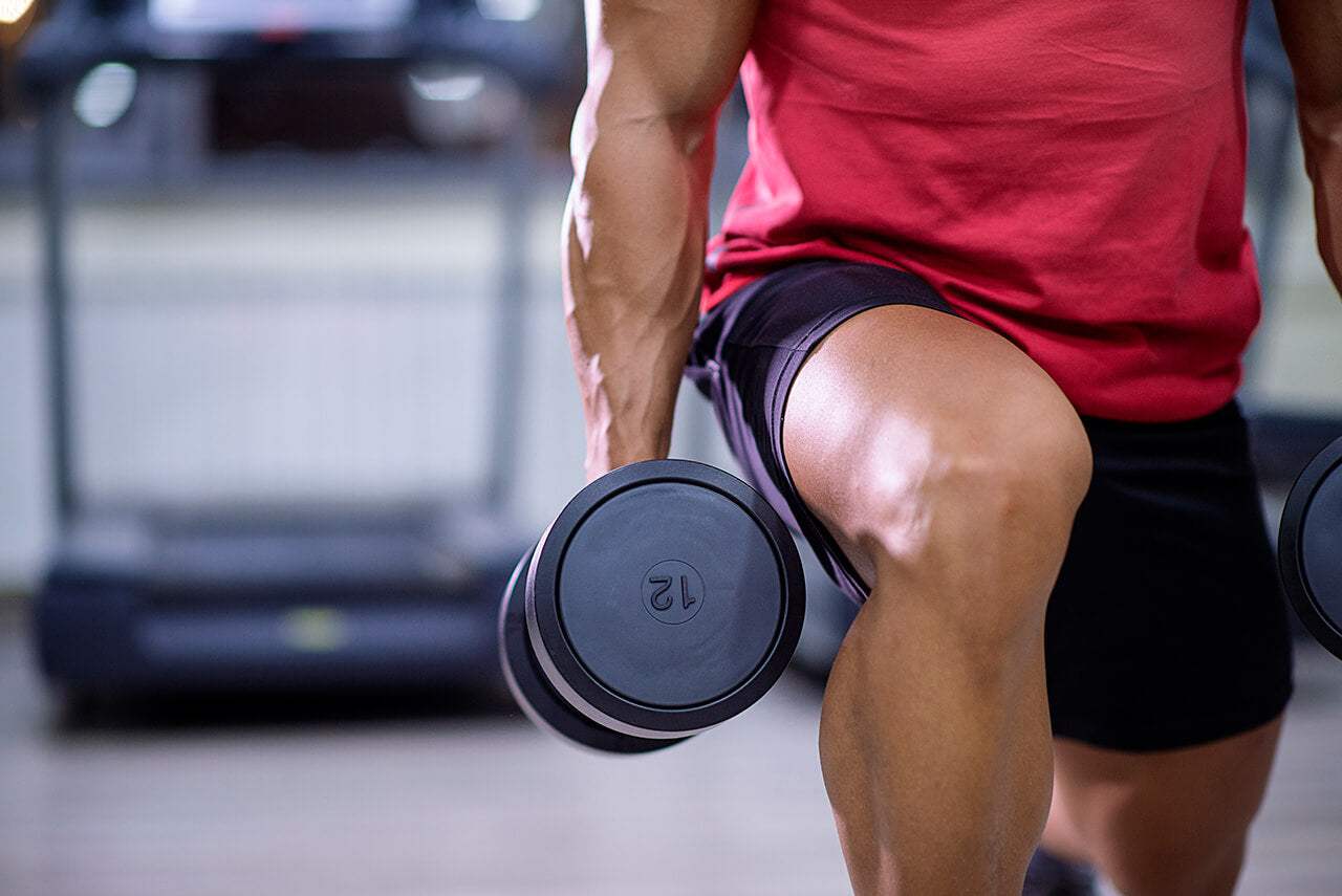 man lunging with dumbbells may take vitamins for muscle growth