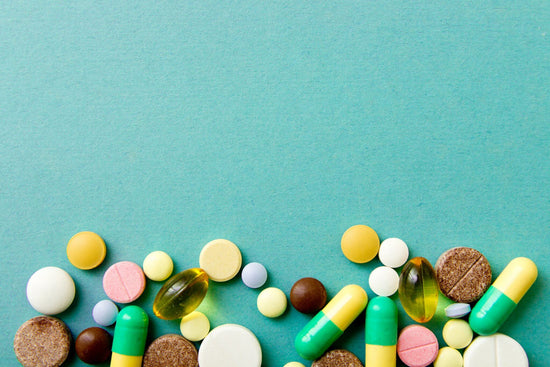 Many colorful pills on red background with copy space