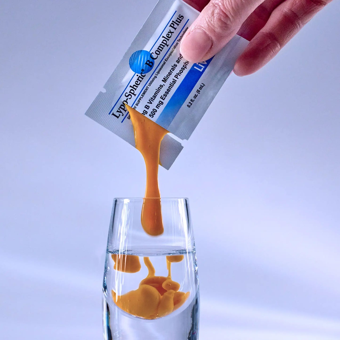 hand squeezing Lypo-Spheric® B Complex Plus into a shot glass