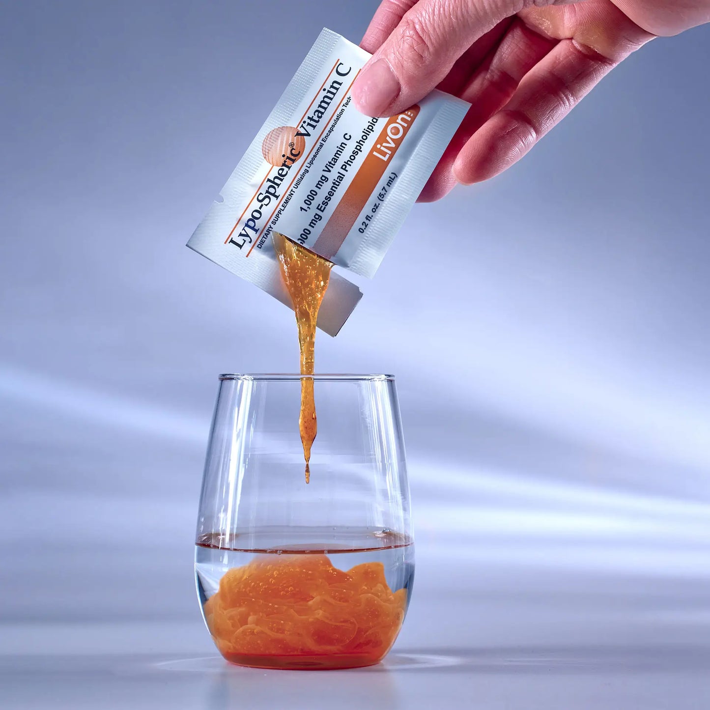 hand squeezing Lypo-Spheric® Vitamin C into a shot glass