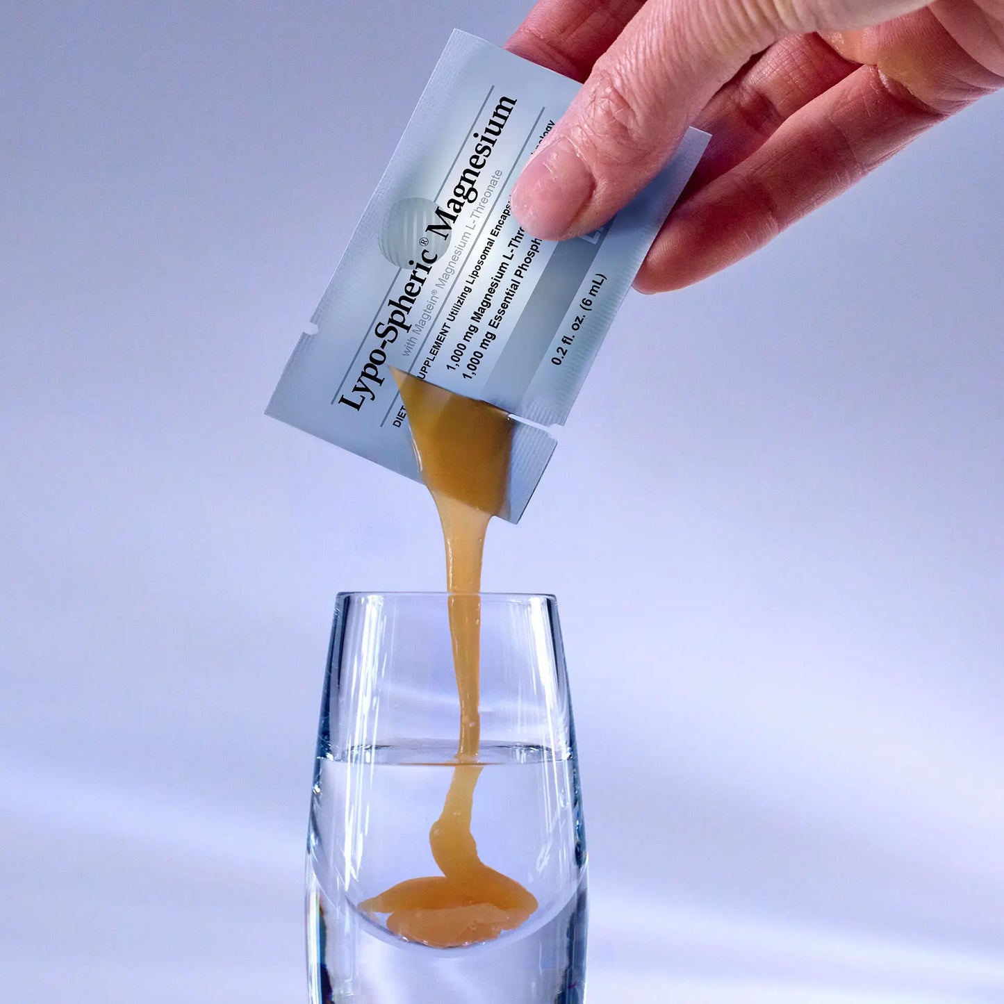 hand squeezing Lypo-Spheric® Magnesium into shot glass