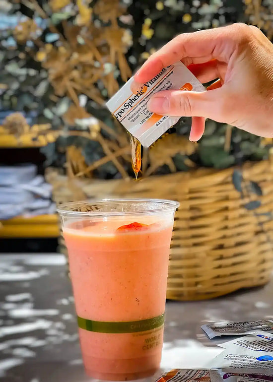 hand squeezing lypo-spheric vitamin c into a smoothie