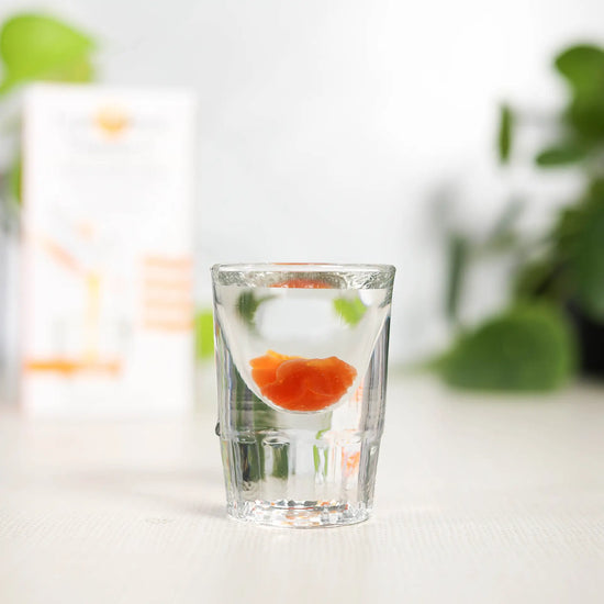 shot glass of lypo-spheric vitamin c with carton in background