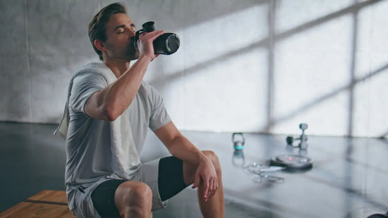 Man drinking from a water bottle in a modern indoor setting
